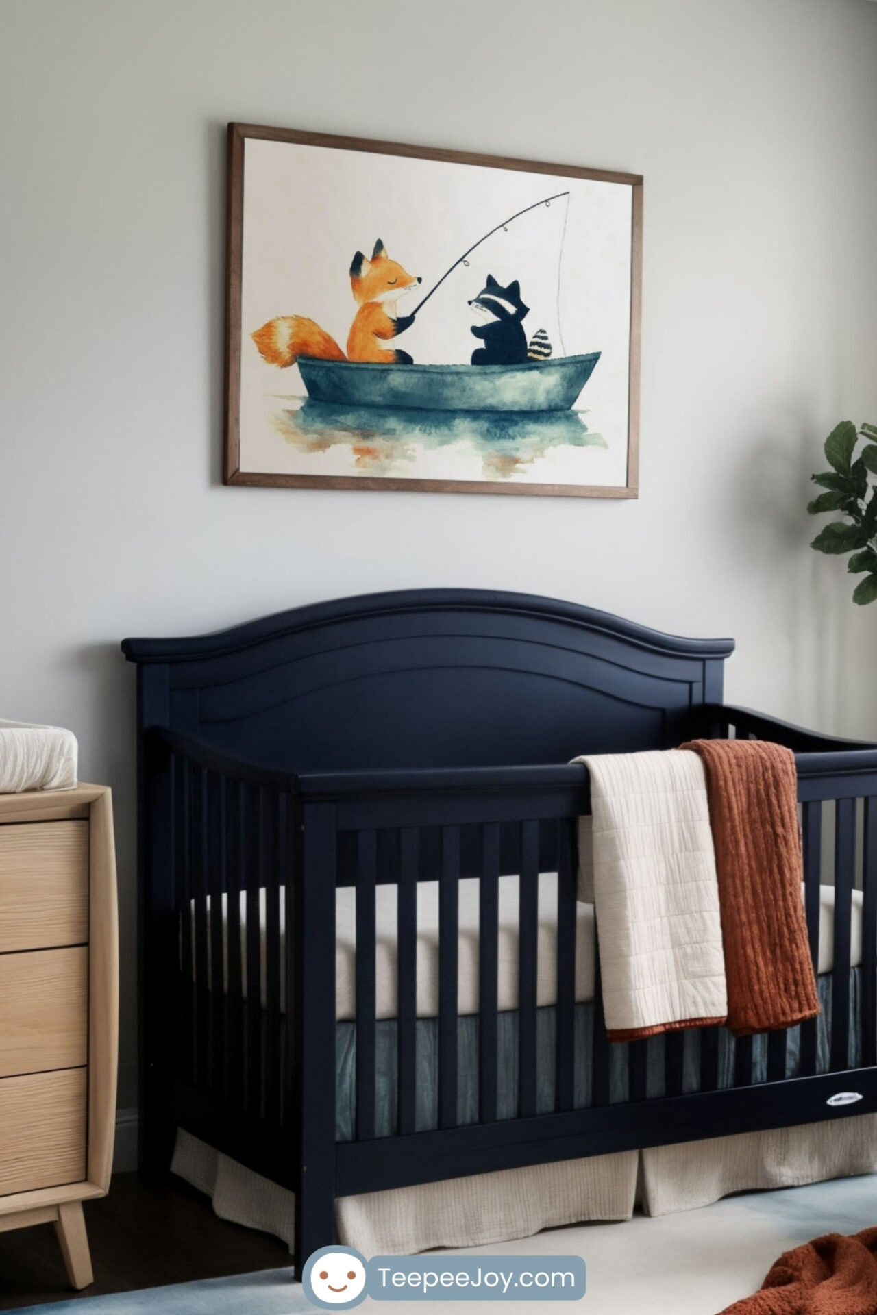 Cozy and modern nursery featuring a navy blue crib with a cream and burnt orange blanket draped over the side. A framed watercolor-style illustration of a fox and raccoon fishing in a boat hangs above the crib, complementing the room’s warm and earthy tones. The space is decorated with a wooden dresser, a white armchair with an orange throw pillow, woven baskets, and a soft watercolor-patterned rug, creating a serene and inviting atmosphere.