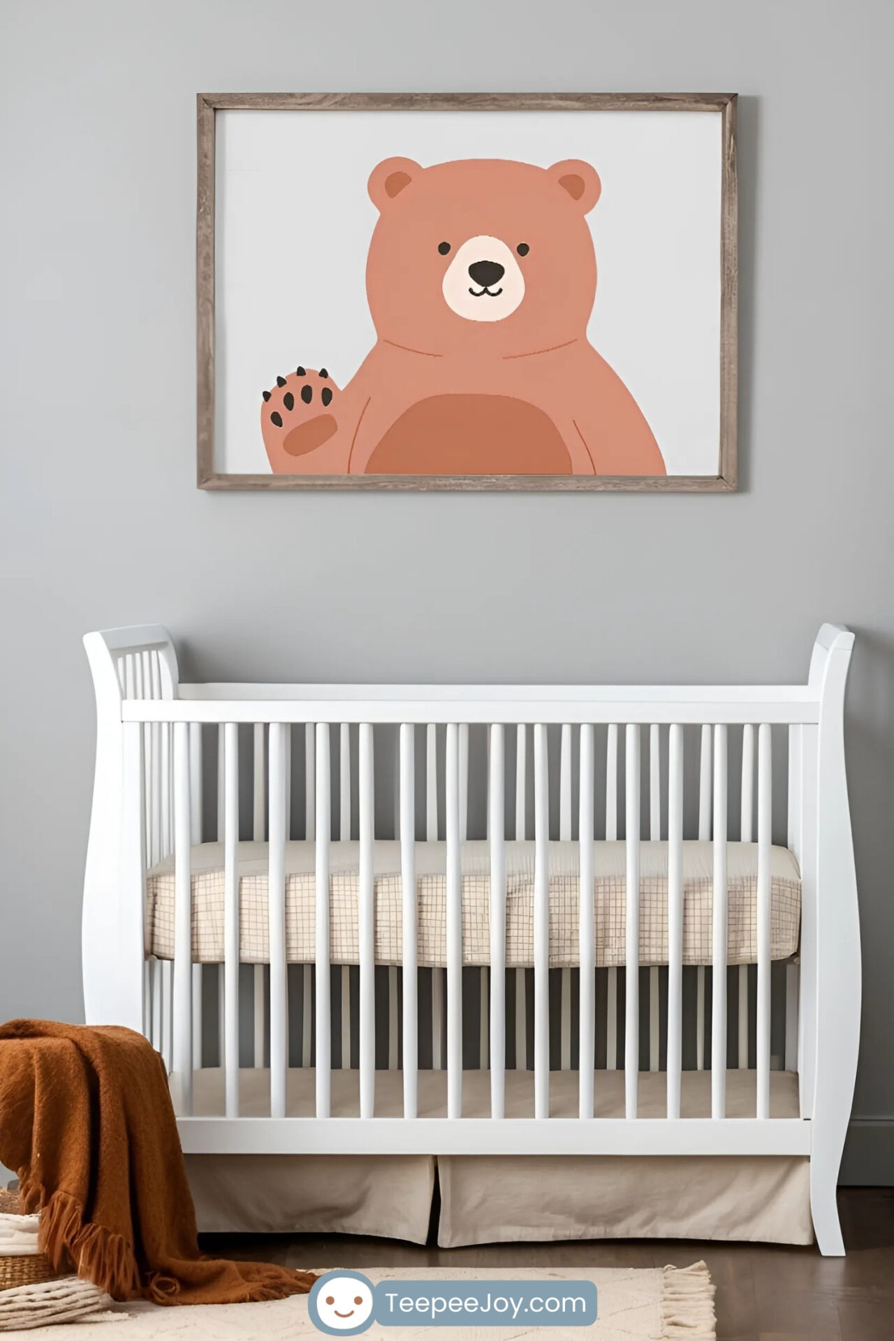 A cozy nursery with a white crib featuring a beige mattress, a rocking chair with a cream cushion, and a rustic wooden wall art of evergreen trees. A framed illustration of a waving bear in soft brown tones hangs on the gray wall above the crib, adding a warm and playful touch to the serene decor.
