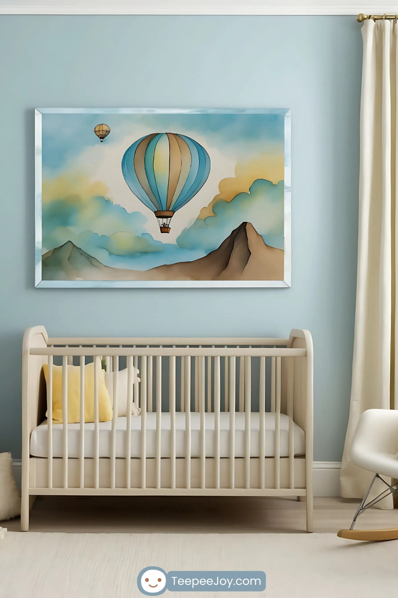 Serene nursery with a soft beige crib and light yellow accent pillows, set against a sky-blue wall. Above the crib hangs a whimsical hot air balloon painting featuring two balloons floating among pastel clouds and mountains.