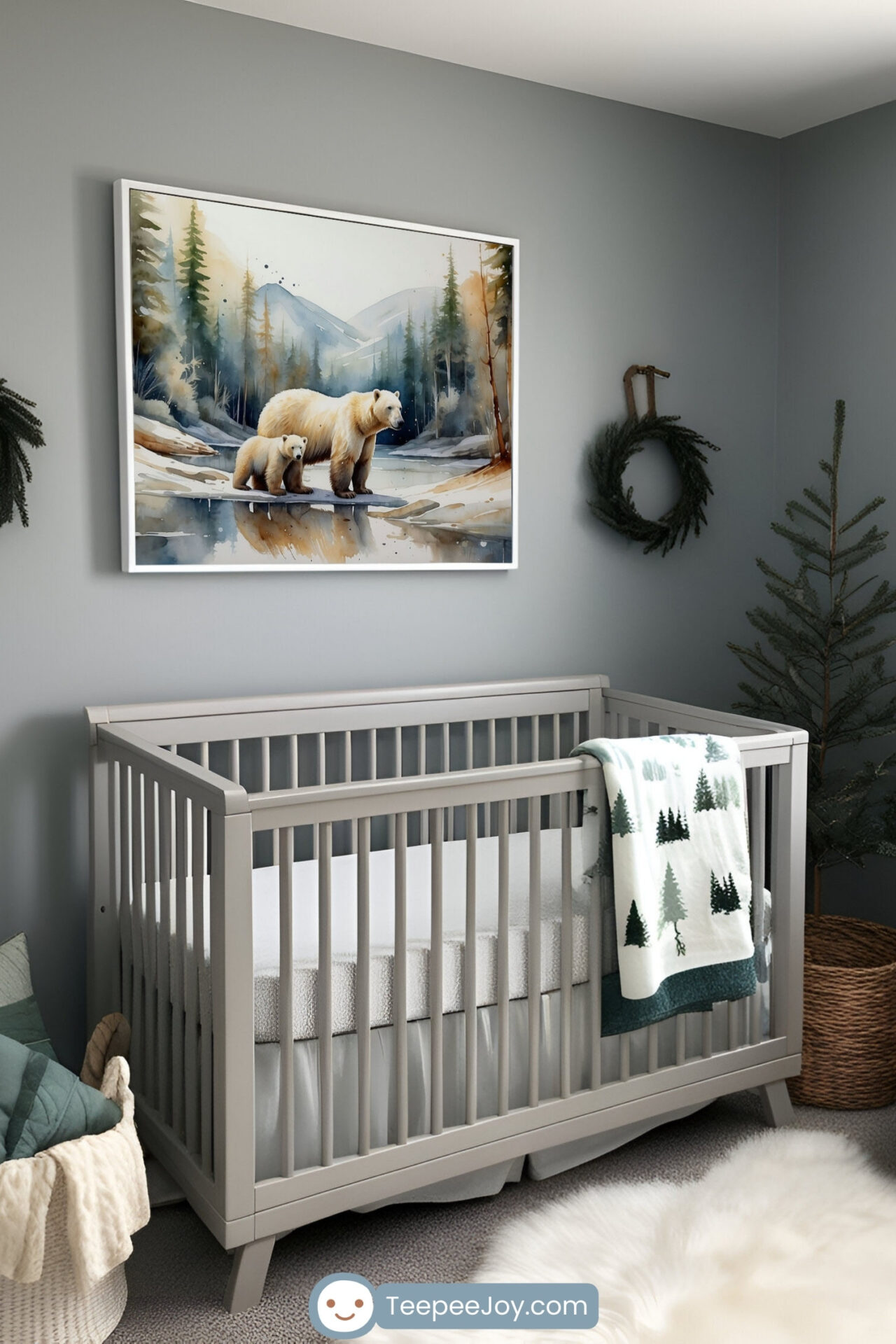 Modern nursery decorated in a woodland theme featuring a light gray crib with a soft white mattress and a fleece blanket draped over the side, patterned with evergreen trees. Above the crib hangs a framed watercolor painting of a polar bear and cub standing beside a snowy forest stream, with mountains in the background. The room is accented with pine wreaths, a small artificial tree, and neutral-toned textures for a calm, nature-inspired feel.