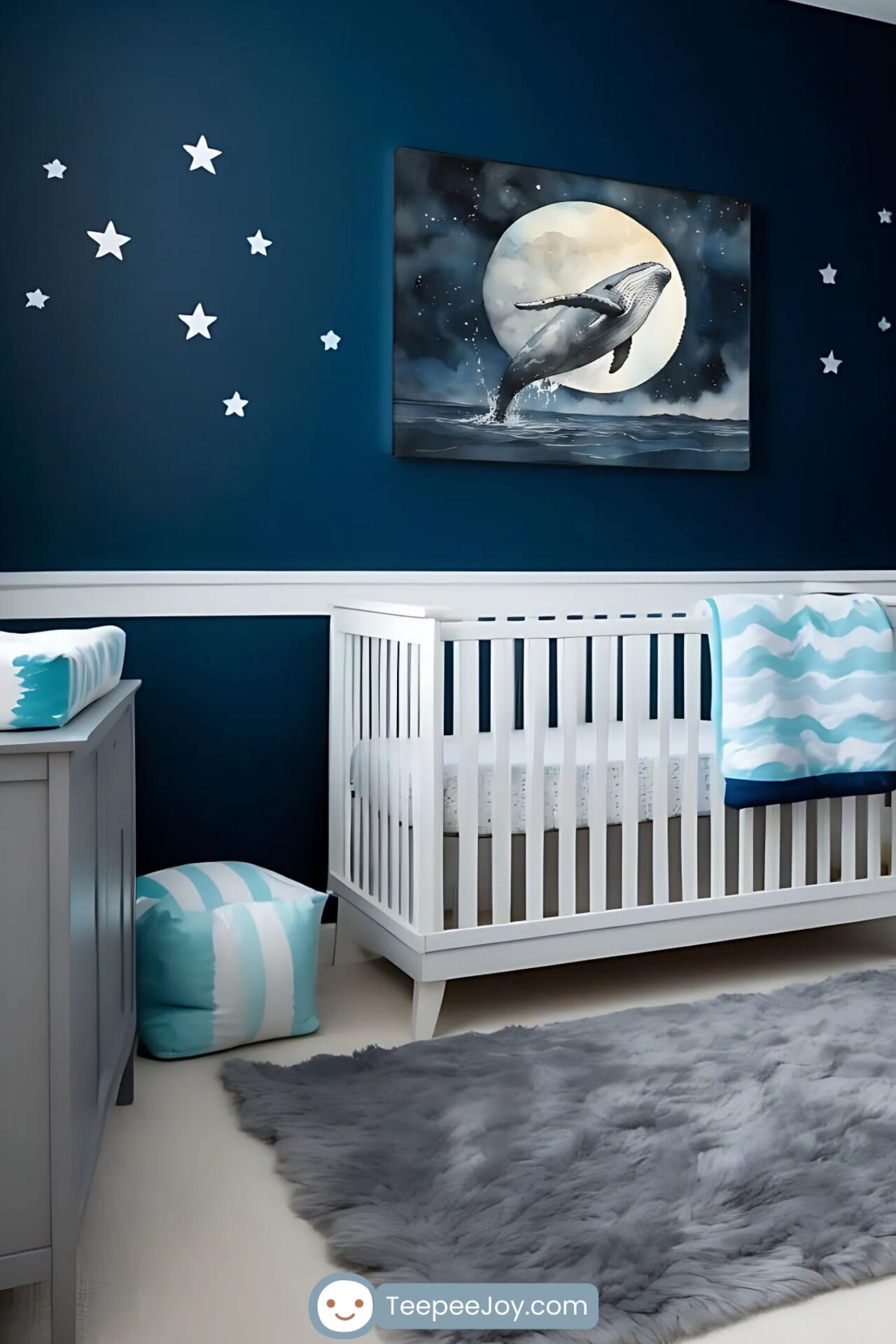 This image features a celestial-themed nursery with deep navy blue walls adorned with star decals and a moon motif. A framed watercolor illustration of a humpback whale breaching under a full moon is the focal point above a white crib. The room is styled with soft gray and white furniture, including a cozy rocking chair with wave-patterned pillows, a plush gray rug, and accents in aqua and light blue for a dreamy and serene atmosphere.